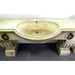 A reconstituted stone horse trough form sink, with large metal rings to the front,