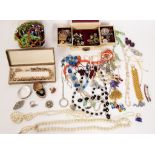 A quantity of costume jewellery including bead necklaces, silver bangle, enamelled brooches etc.