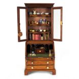 An apprentice miniature bureau bookcase, 56cm high, containing miniature books, pottery etc.