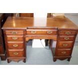 An Edwardian mahogany twin-pedestal desk, fitted a surround of nine drawers,