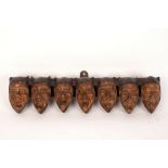 A pipe rack for seven pipes, the supports in the form of jester mask heads,