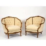 A pair of walnut upholstered armchairs with deep button backs