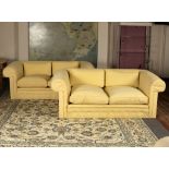 A pair of upholstered two-seater sofas with buttoned divan backs,