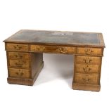 A late Victorian oak pedestal desk fitted a surround of nine drawers,