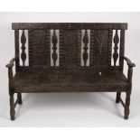 A 17th Century style oak settle, with carved splat back, carved front rail and on turned legs,