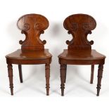 A pair of Victorian mahogany hall chairs with cartouche shaped backs on turned front legs