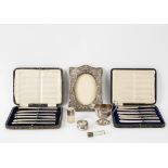 An embossed silver photograph frame, Birmingham 1905, a half-ribbed cream jug, two scent bottles,