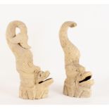 A pair of carved stone dolphins with open mouths on rock type bases,
