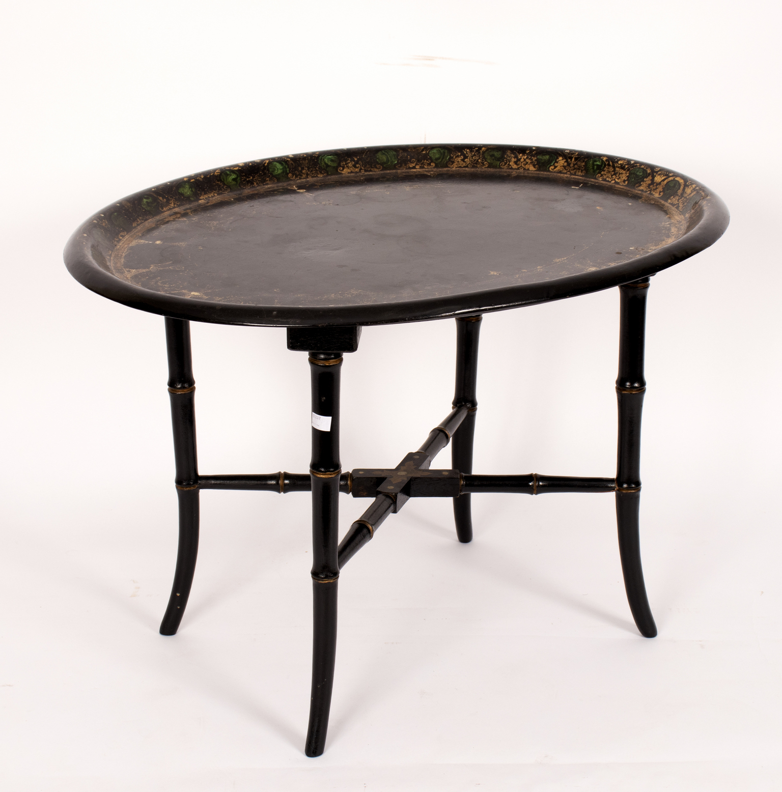 An oval papier-mâché tray, mounted as a table on faux bamboo legs,