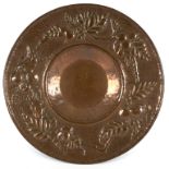 A Newlyn School copper charger, repoussé decorated with border of stylised pomegranates and foliage,