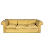 A large modern three-seater sofa with loose cushions covered in buttercup yellow fabric,