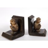 A pair of wooden bookends, each carved as a monkey sitting between the open pages of a book,