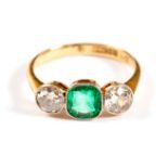 An emerald and diamond three-stone ring, the emerald flanked by diamonds of approximately 0.