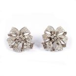 A pair of diamond ear studs, each of ribbon tie form centred by a seven-stone cluster,