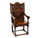 A Charles II oak open armchair, the scrollwork carved back with triple panels of S-scroll,