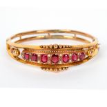 An Edwardian ruby and pearl hinged bangle set in 9ct yellow gold,