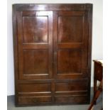 An 18th Century oak wardrobe, enclosed by a pair of panel doors with two short drawers under,