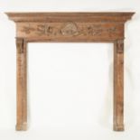 A pine fire surround with shell and scroll carved frieze on bracket supports above trails of