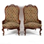A pair of Victorian fireside chairs with pierced carved walnut frames,
