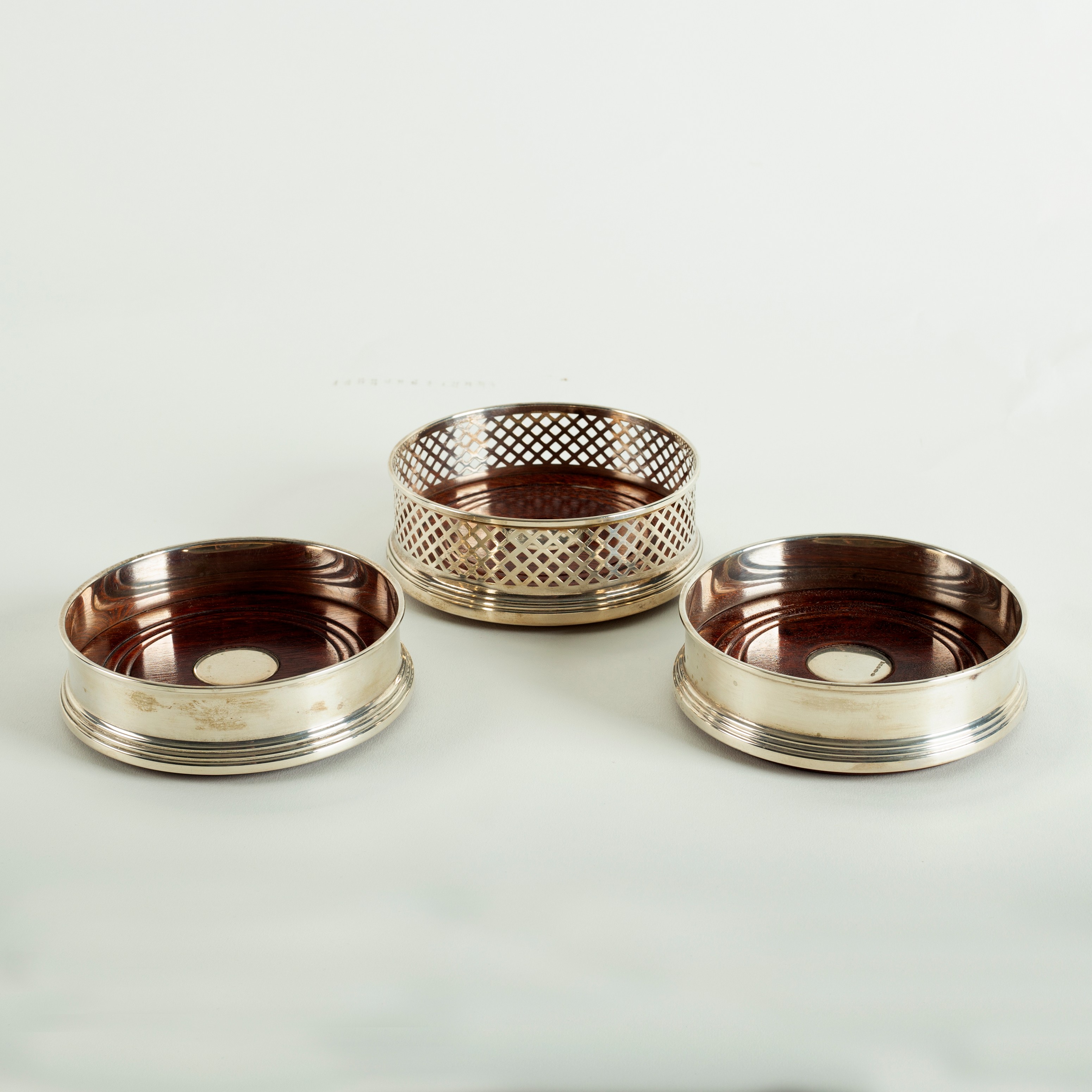 A pair of modern silver wine coasters and another with pierced sides