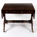 A Regency mahogany sofa table, on turned end supports the outswept legs on brass caps and castors,