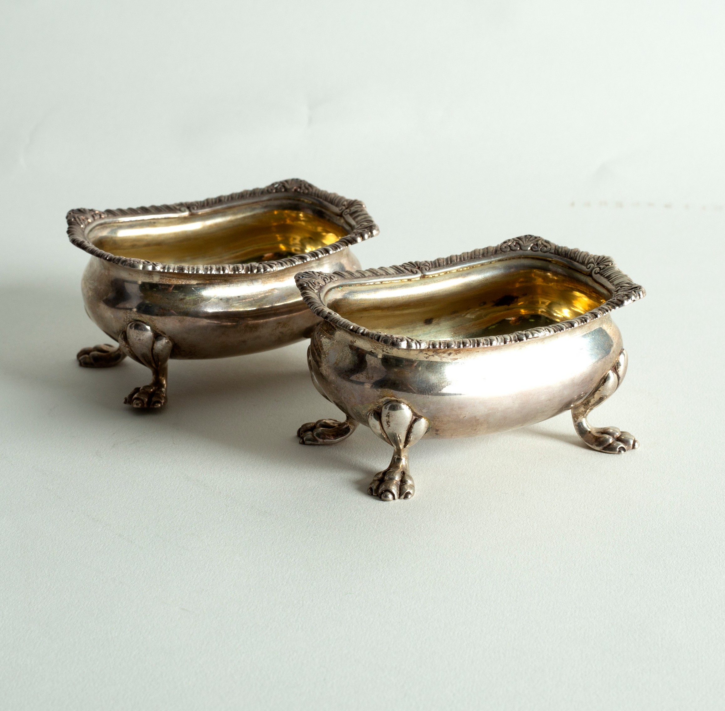 A pair of 18th Century style silver salts, with gadrooned rims on paw feet, 10cm wide,