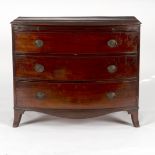 A Regency mahogany bow front chest, fitted a brushing slide over three long drawers on splay feet,
