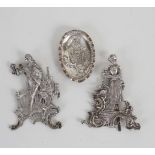 A pair of white metal figures, gallant with companion, on easel supports,