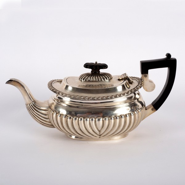 A silver teapot, J & C, Birmingham 1904, of half-ribbed form with ebonised handle and finial,