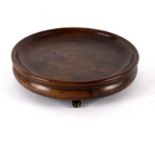 A Georgian circular mahogany coaster on three barrel feet,