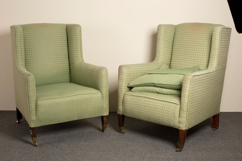 A pair of 19th Century upholstered wing armchairs on square taper front legs with brass caps and
