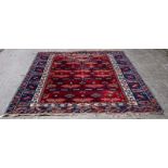 An Afghan carpet of geometric design to a plum ground within a blue border,