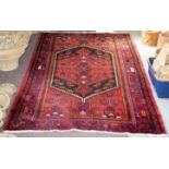 An Eastern style rug of crimson ground with a geometric centre field,