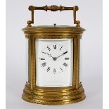 A gilt brass carriage clock in an oval engraved case,