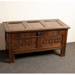 A carved oak chest with triple-panel top,