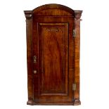 An early 18th Century walnut arch-top corner cupboard, enclosed by a carved panel door,