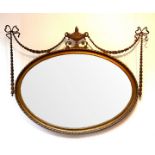 An oval gilt framed mirror with urn crest and swagged decoration, the plate 105.