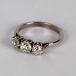A diamond three-stone ring, claw set in precious white metal, the central stone approximately 0.