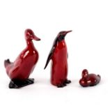 A Royal Doulton flambé figure of a duck, 16cm high, a penguin, 15cm high and a swimming duck,