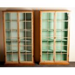 A pair of pine display cases, each enclosed by a pair of glazed doors,