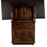 A carved oak cabinet, the upper and lower sections enclosed by panel doors,