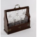 An Edwardian oak cased tantalus fitted three cut glass decanters,