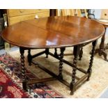 An oval oak gateleg table with twin-flaps, raised on eight spiral turned legs united by stretchers,