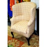An upholstered armchair with concave back on cabriole legs