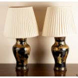 A pair of black and gold lacquer vase shaped table lights with shades,