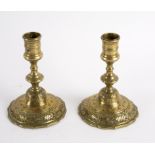 A pair of engraved brass candlesticks on skirt bases, 14.