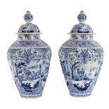 A large pair of Delftware blue and white vases and covers painted scenes representing the four