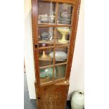 An Art Deco style limed oak display cabinet with four shelves enclosed by a glazed bar door,