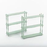 A pair of green painted hanging shelves on spindle turned supports,