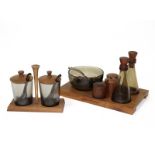 A Danish style condiment set in two parts, each with wooden base fitted smoked glass bottles,